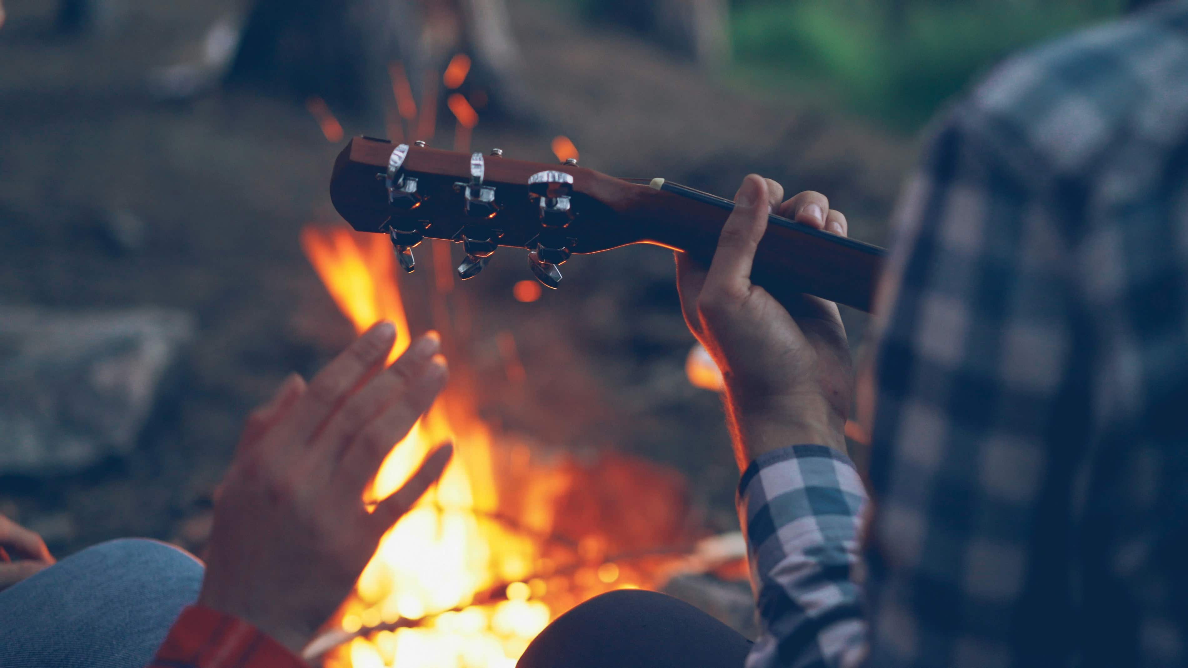 People playing guitar by a campfire at night